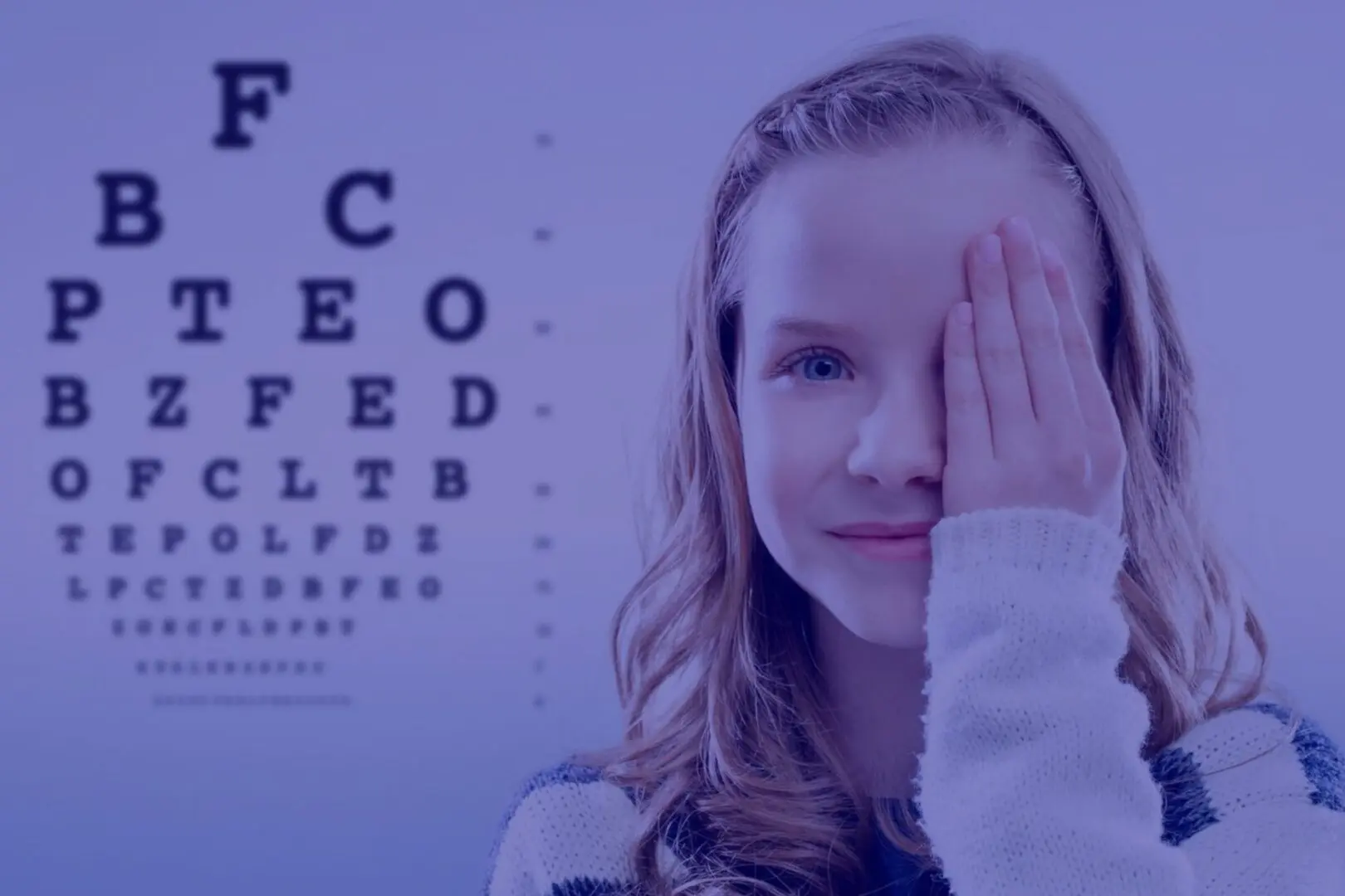 A girl covering her eyes with an eye chart in the background.